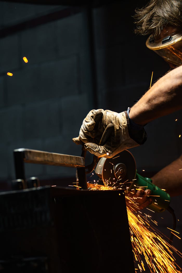 Home Close-up of a worker using a grinder on metal, creating vivid sparks in a workshop.