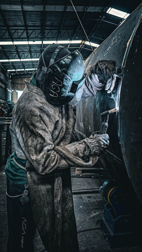 pexels photo 30431684 1 A welder in protective gear welding metal structures in a factory environment.